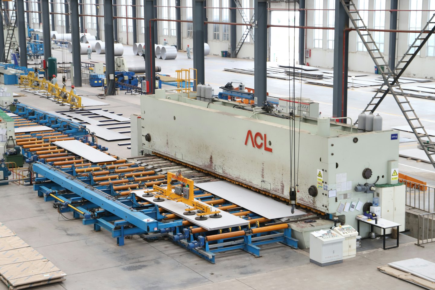 Automatizované stroje spracúvajú plechy na podlahe továrne.